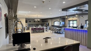 Une cuisine moderne dotée d’un îlot central, d’un coin repas avec plusieurs chaises et d’un bar avec un comptoir éclairé de lumière bleue.