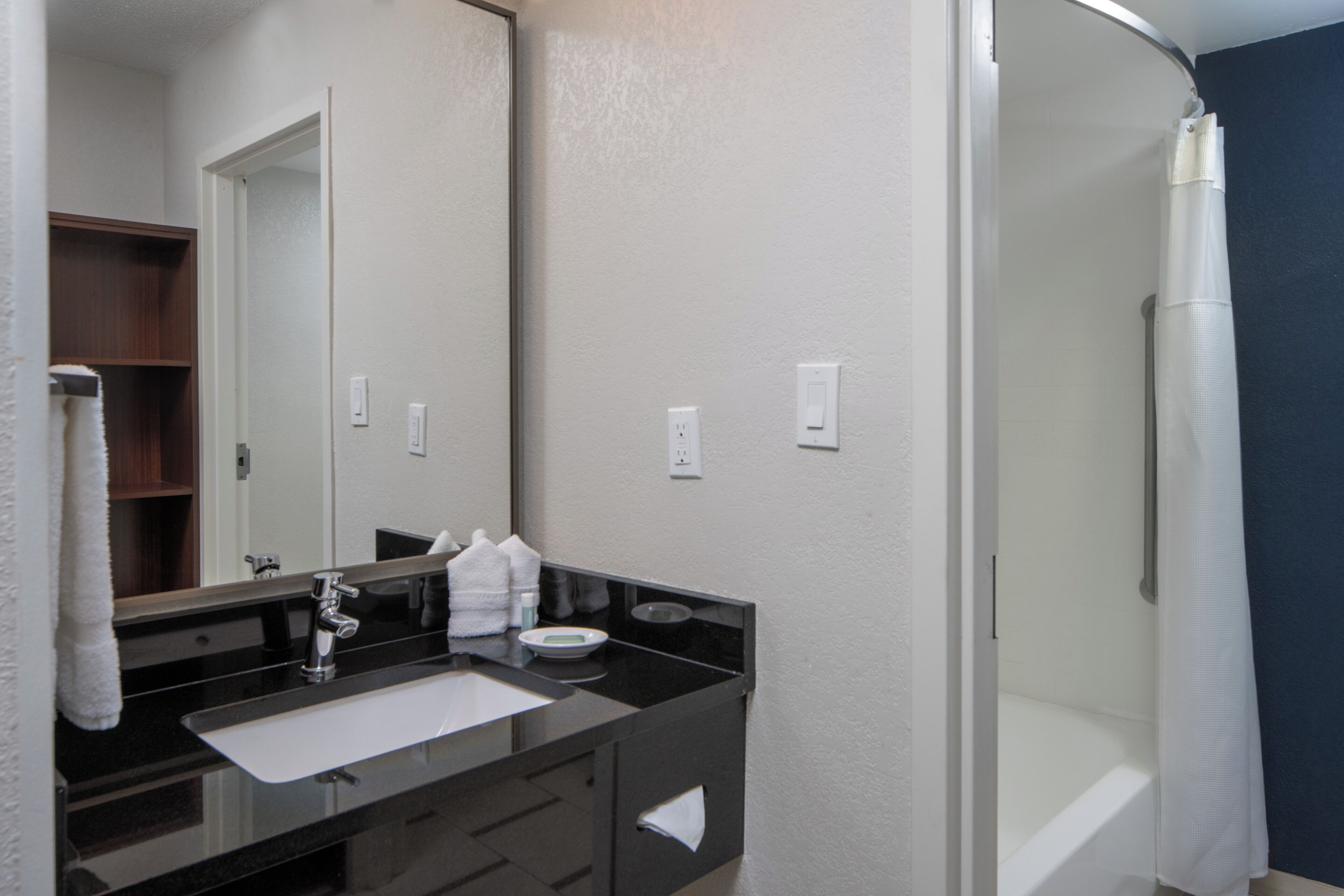 A bathroom with a sink, mirror, towel rack, and a shower curtain.