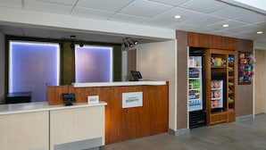 Zona de recepción de un hotel con un mostrador de madera, un teléfono digital y un dispensador automático de bebidas.
