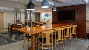 Un salón de conferencias con una gran mesa de madera, varias sillas e iluminación colgante.