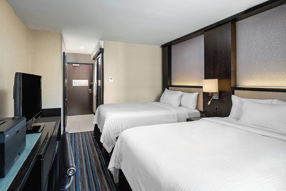 Habitación de hotel con dos camas, televisor y escritorio con impresora.