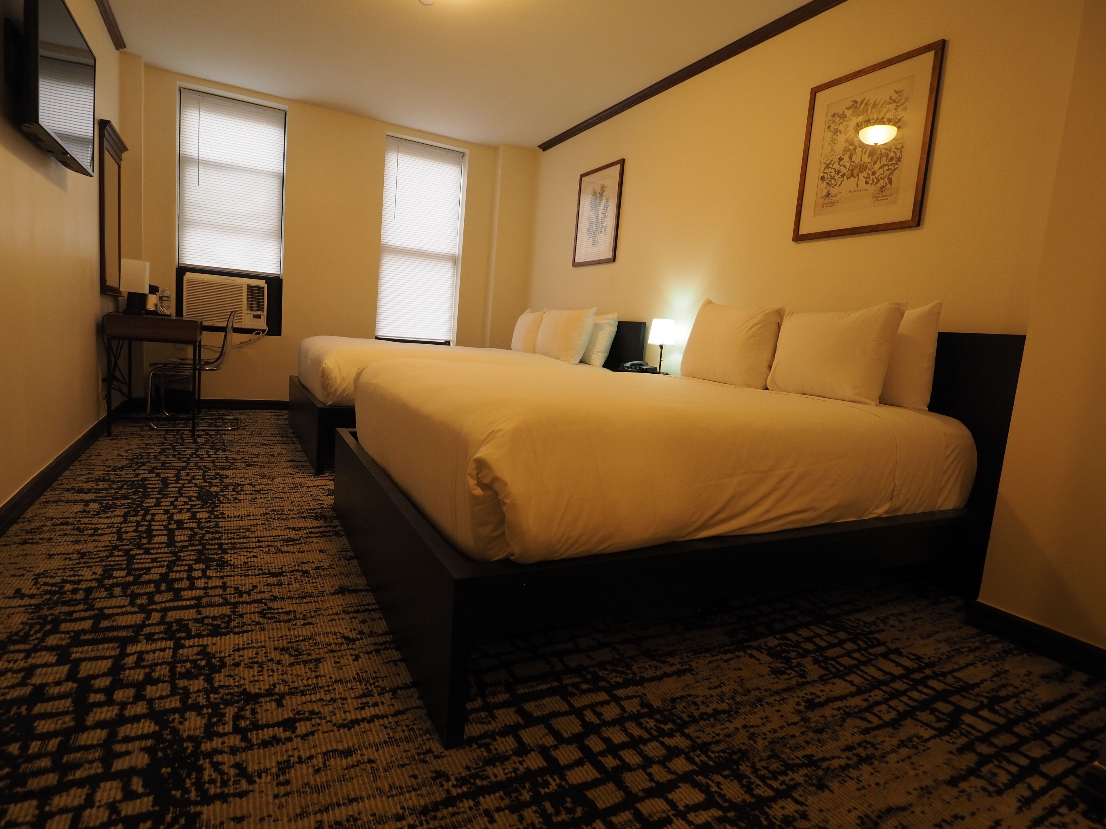 Une chambre d’hôtel avec deux lits, un bureau et une chaise.