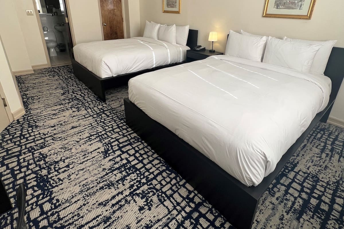 Hotellihuone, jossa on kaksi sänkyä, kylpyhuone ja käytävä.