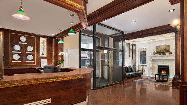 A reception area with a wooden reception desk, a fireplace, and a seating area with a sofa and armchairs. - Night Hotel Broadway (New York)
