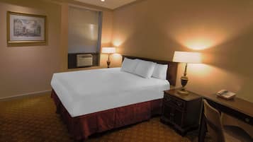 Habitación de hotel con una cama grande, dos lámparas de noche, un escritorio con teléfono y un cuadro en la pared.