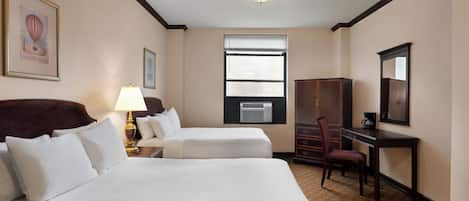 Een hotelkamer met twee bedden, een bureau, een stoel, een garderobe, een lamp en een raam.