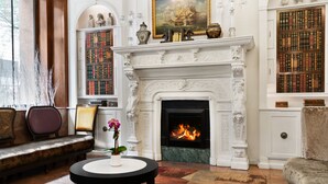 A library with bookshelves, a fireplace, and a sofa. - Night Hotel Broadway (New York)