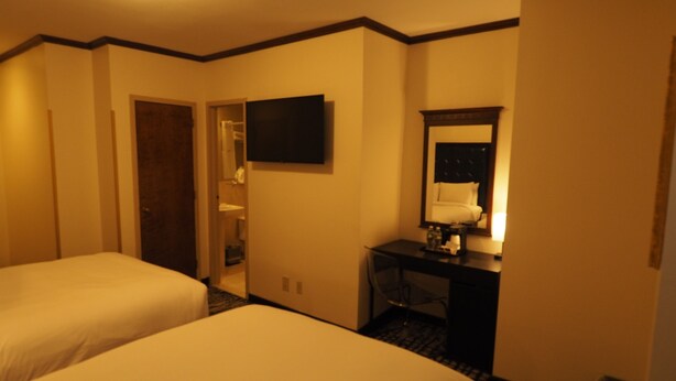 A hotel room with two beds, a desk, a mirror, and a television. - Night Hotel Broadway (New York)