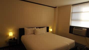 Una camera d'albergo con un letto, lampade ai comodini, un telefono e un condizionatore d'aria.