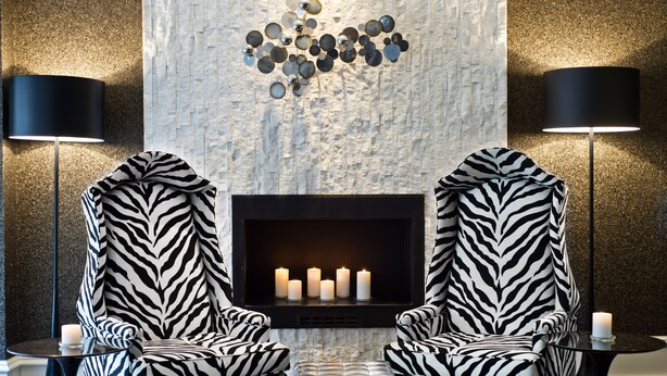 Un área lounge moderna con dos sillones de estampado de cebra frente a una chimenea con velas.