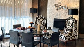 Un comedor moderno con una mesa redonda de vidrio, sillas negras y un sillón estampado con diseño de cebra.
