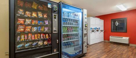 Two vending machines with snacks and drinks, a red wall, and a wooden floor.