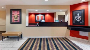 A hotel reception area with a reception desk, a bench, and a striped carpet.
