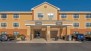 A hotel lobby with a clear entrance, a sign indicating the lobby, and a parking area with cars.