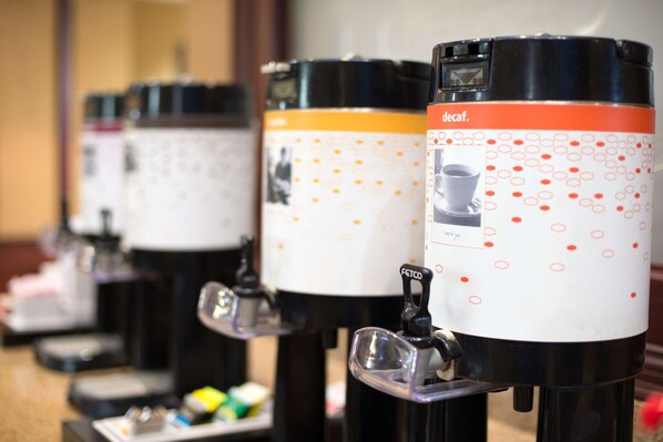 A row of coffee dispensers with a white and orange design, labeled 'decaf.'