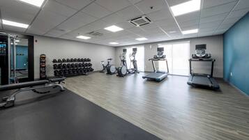 A gym with treadmills, elliptical machines, and a variety of weights.