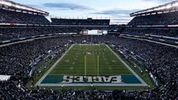 A football stadium with a large crowd, a football field, and the word "Eagles" on the field.
