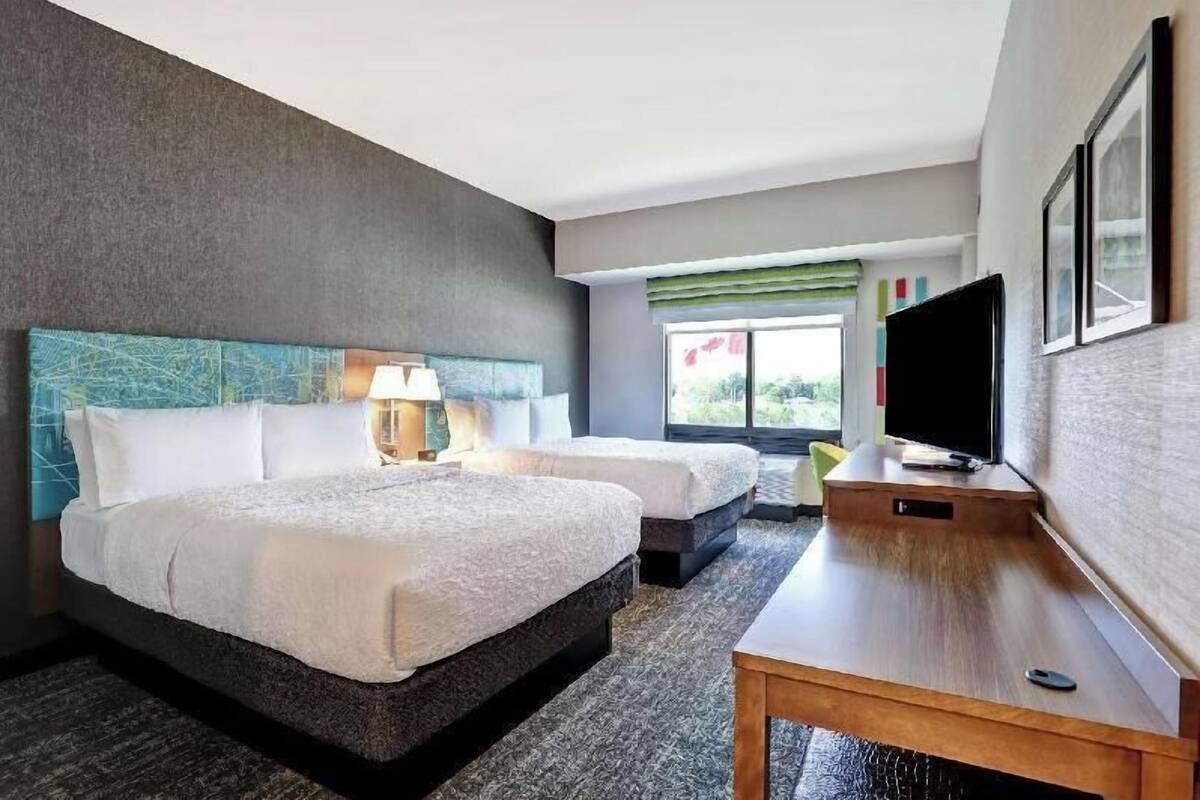 A hotel room with two beds, a television, and a window with a view.