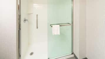 A glass-enclosed shower with a towel rack and a visible drain.
