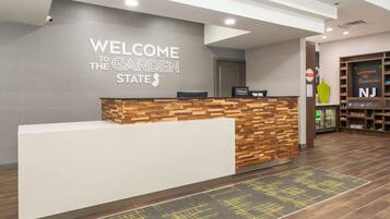 A reception desk with a wooden and white design, a sign reading "Welcome to the Garden State," and a "Hilton" sign.
