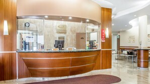 A hotel reception area with a curved wooden counter, a clock, and a sign indicating it is a Choice Hotel.