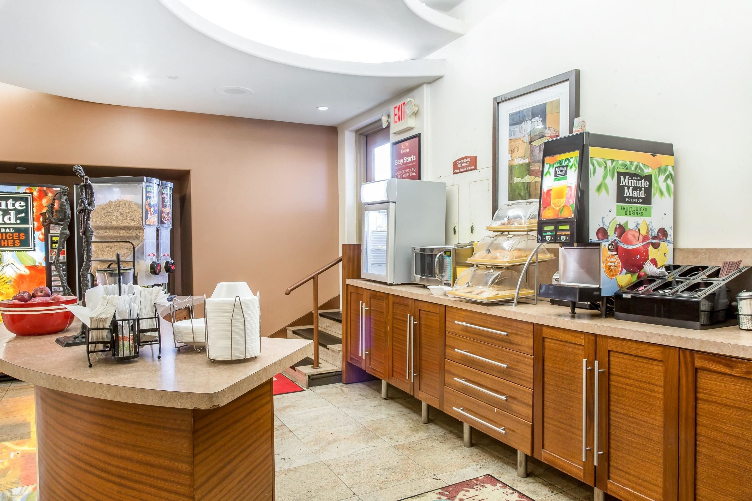 Uma área de recepção de hotel com balcão, micro-ondas, máquina de café e dispensador de suco de fruta.