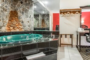 A modern bathroom with a stone wall, a glass bathtub, and a wooden chair. - Econo Lodge West Haven (West Haven)