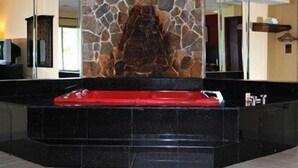A stone wall with a red seating area in the center, surrounded by a black marble platform.