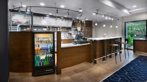 Un bistró moderno con un expositor refrigerado para bebidas, una máquina de café y una pizarra de menú.