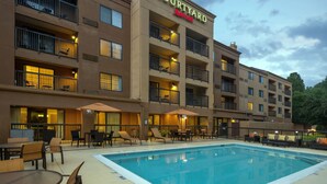 Un hotel Courtyard Marriott con piscina, mobiliario exterior y varios balcones.