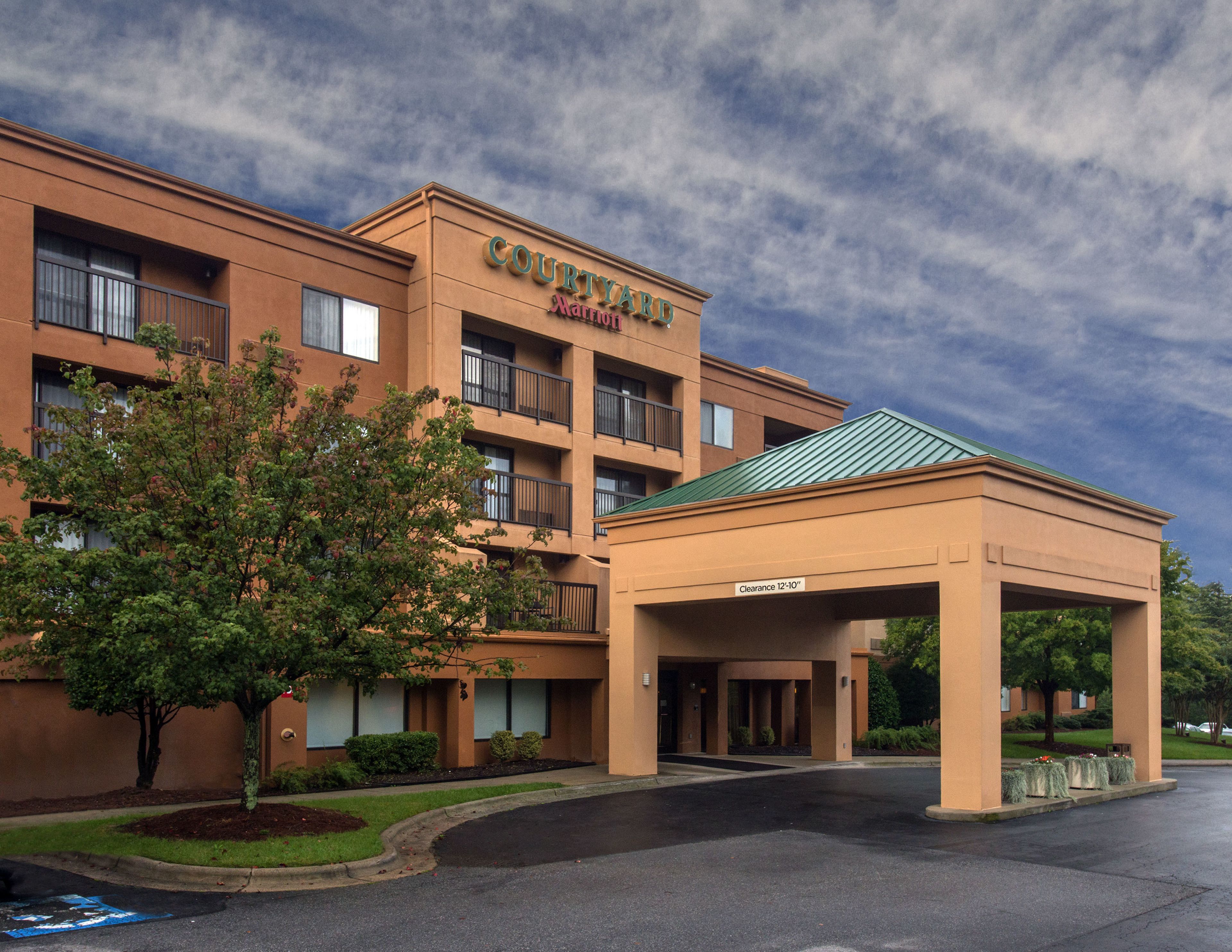 Un hotel Courtyard Marriott con entrada cubierta y aparcamiento.