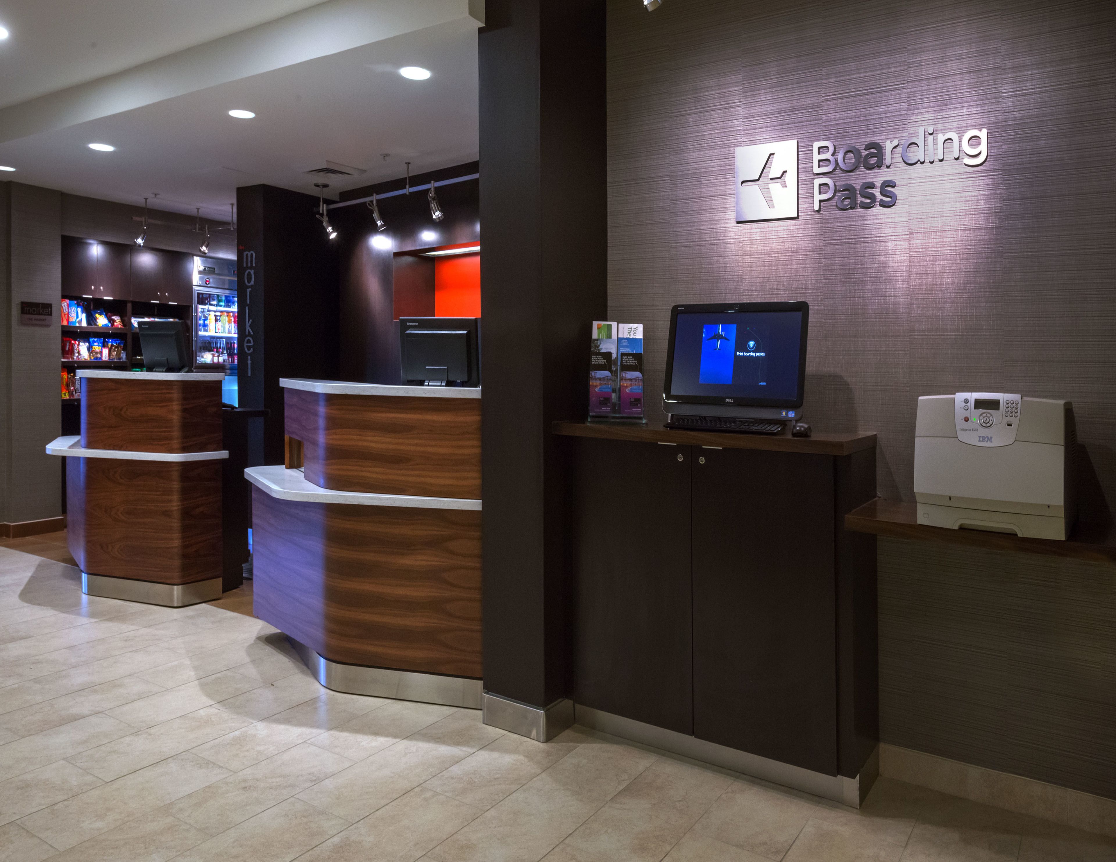 A modern check-in area with a 'Boarding Pass' sign, a computer, and a self-service kiosk.