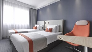 Ein Hotelzimmer mit zwei Betten, einem Schreibtisch und einem Stuhl.