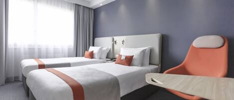 Una habitación de hotel con dos camas, un escritorio y una silla.