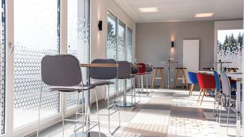 Un intérieur moderne avec un coin salon, de grandes fenêtres et une vue sur les arbres.