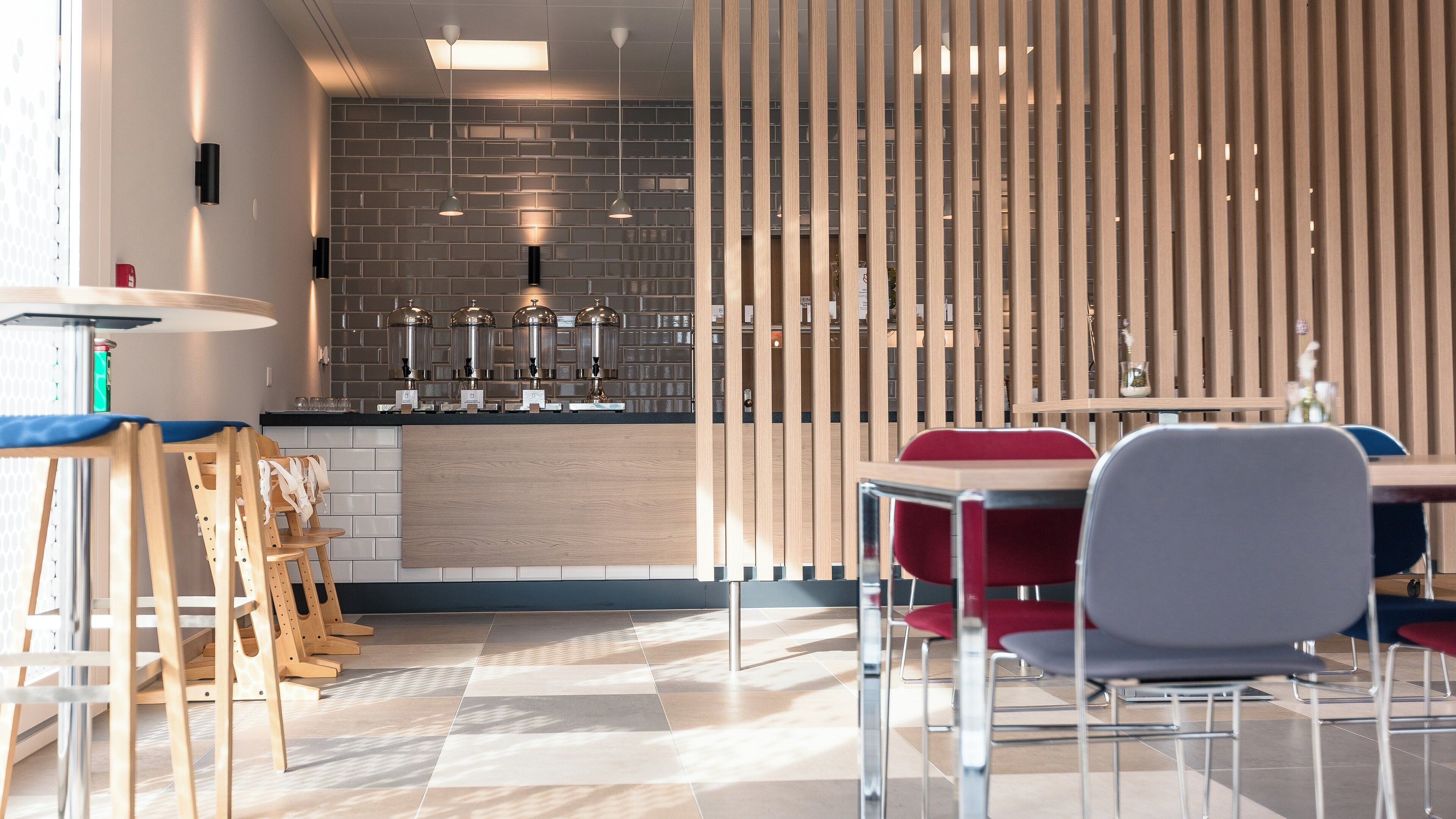 A modern interior with a kitchen area, dining tables, and chairs.
