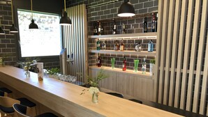 Eine Bar mit einer langen Theke, mehreren Barhocker und einer Auswahl an Flaschen in Regalen.