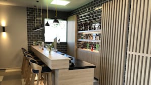 A modern bar area with a long counter, bar stools, and a variety of bottles and glasses. - Holiday Inn Express Luzern - Neuenkirch by IHG (Neuenkirch)