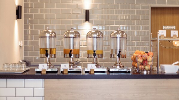 A beverage station with dispensers and a fruit bowl.