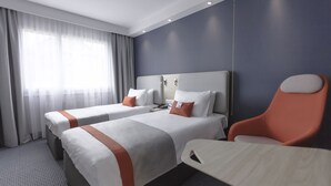 Ein Hotelzimmer mit zwei Betten, einem Schreibtisch und einem Stuhl.