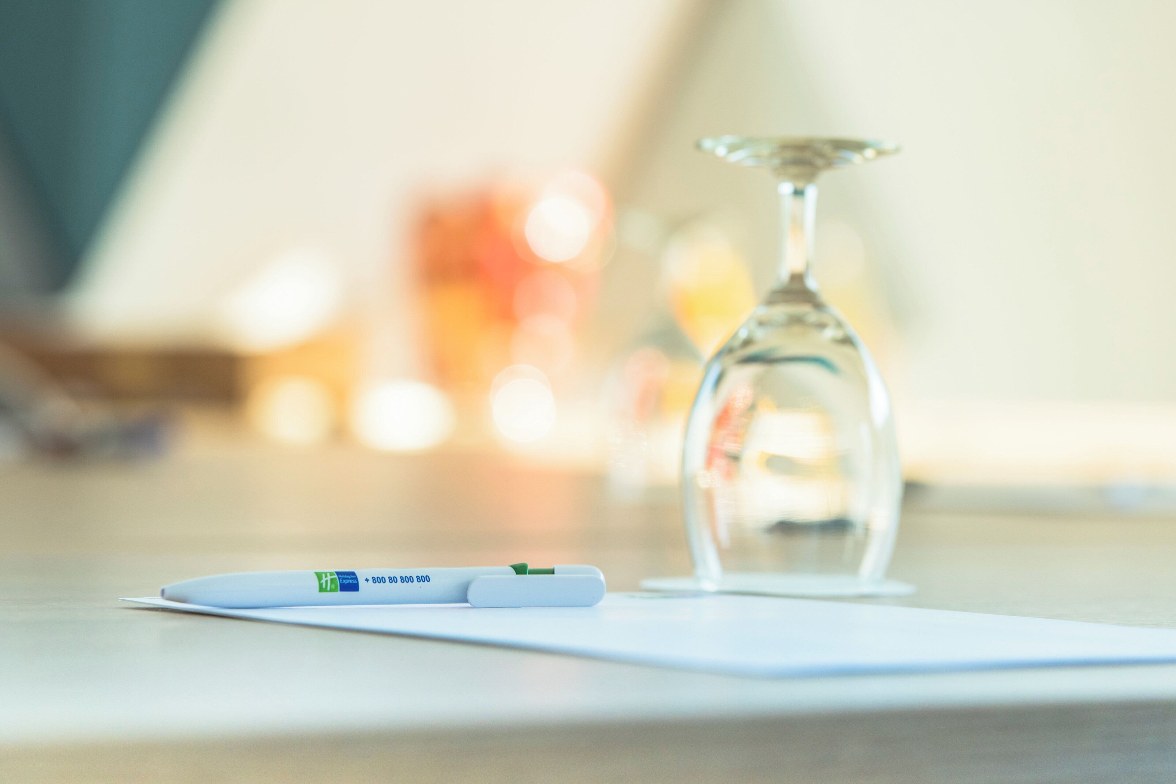 A pregnancy test and a glass of water on a white surface.