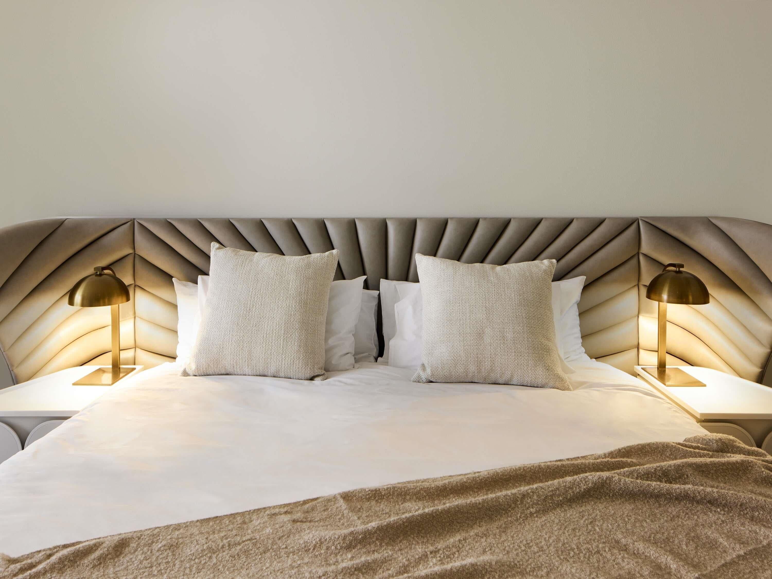 A bed with a tufted headboard, two bedside lamps, and two pillows.