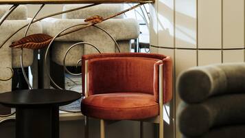 Un intérieur moderne avec un fauteuil en velours rouge, une petite table ronde et une structure métallique originale ornée de motifs de feuilles.