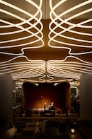 A modern interior with a curved red wall, seating area, and a unique ceiling light design.