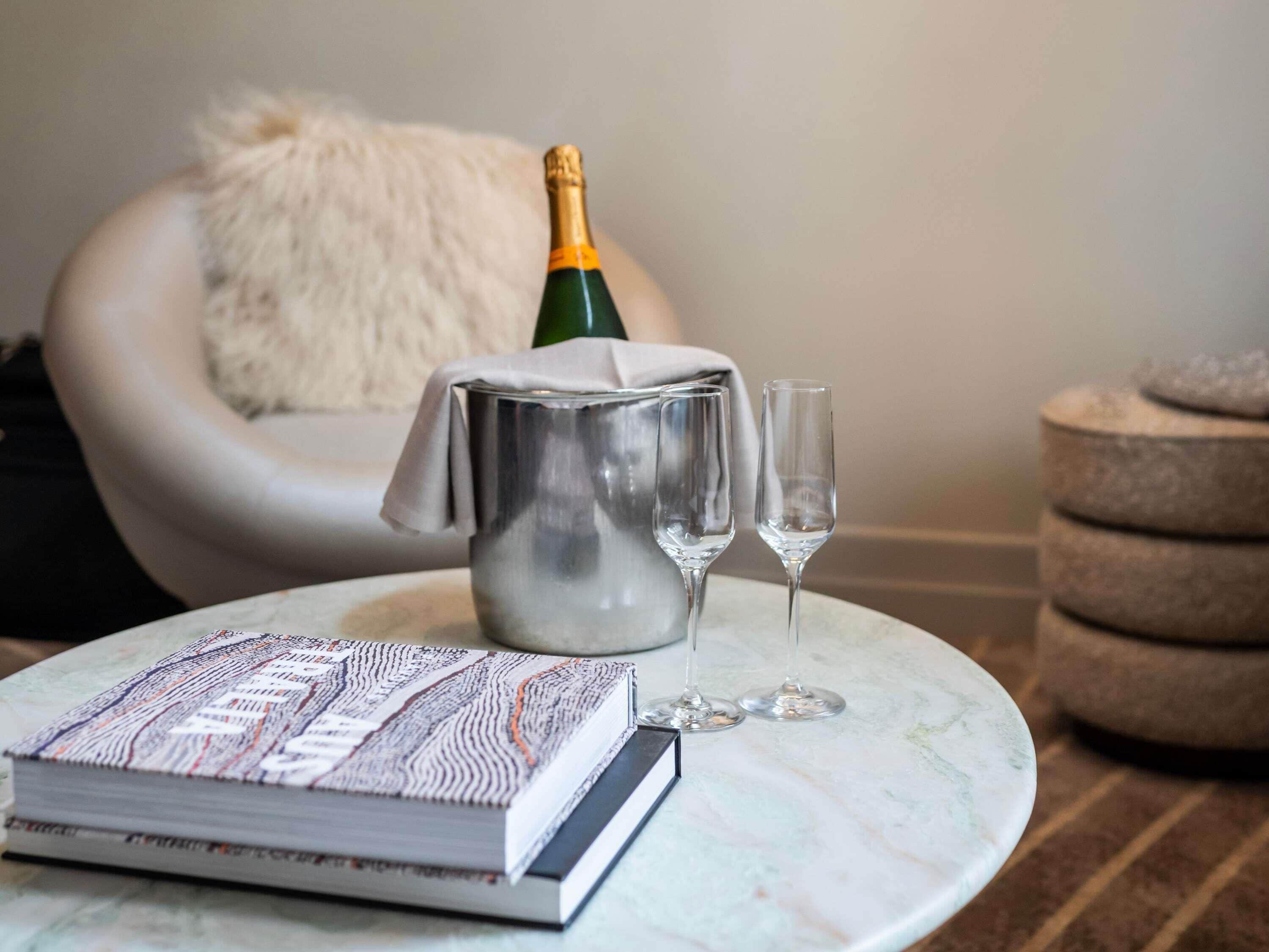 Une table en marbre avec un livre, une bouteille de champagne et deux verres.
