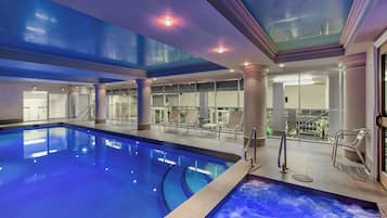 Relax by the pool, surrounded by a seating area and hot tub, with a skylight above.