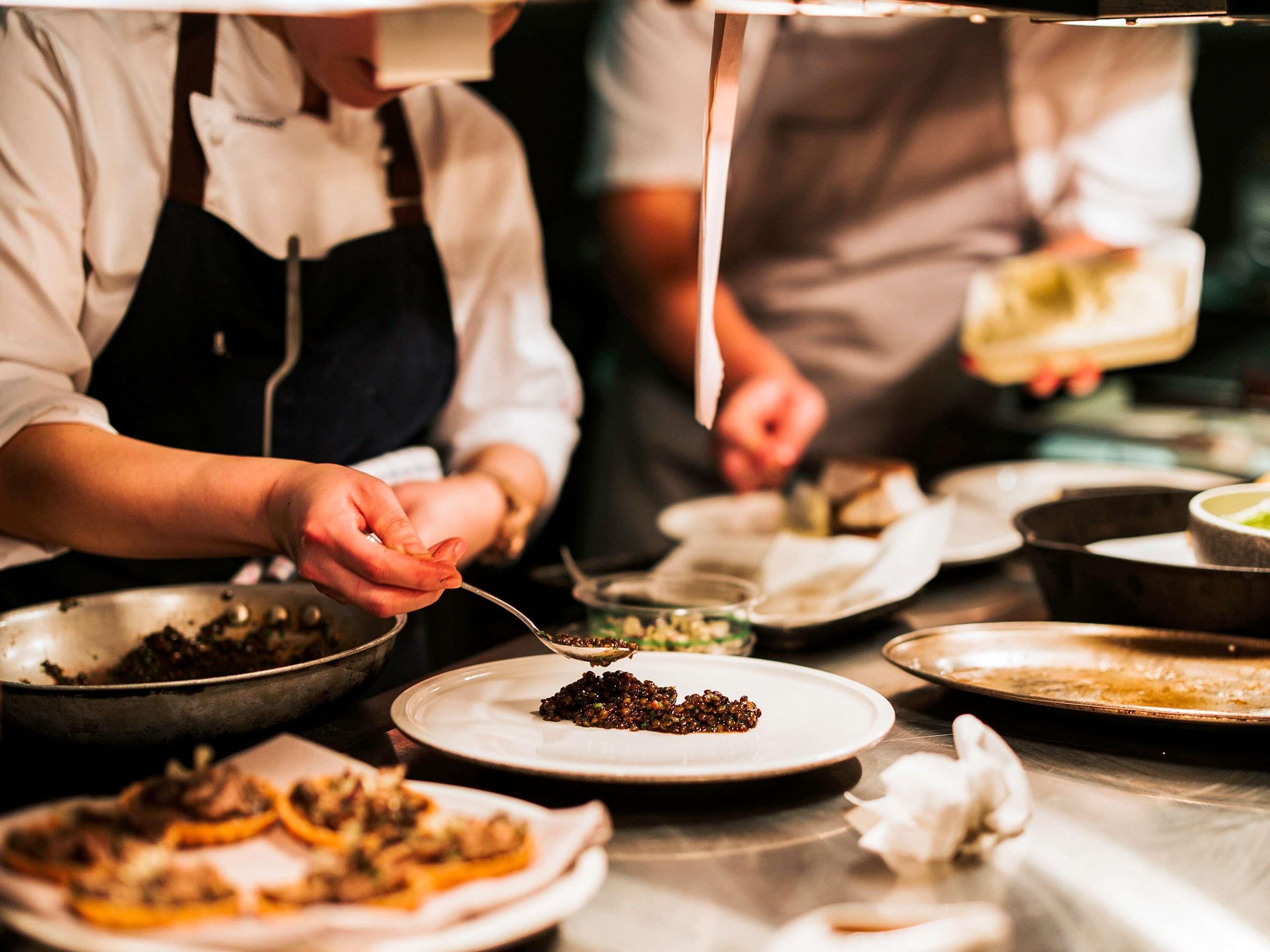 A kitchen scene with chefs preparing dishes.