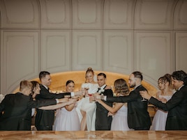 A group of people toasting with champagne glasses in a room with a marble table and ornate wall paneling.