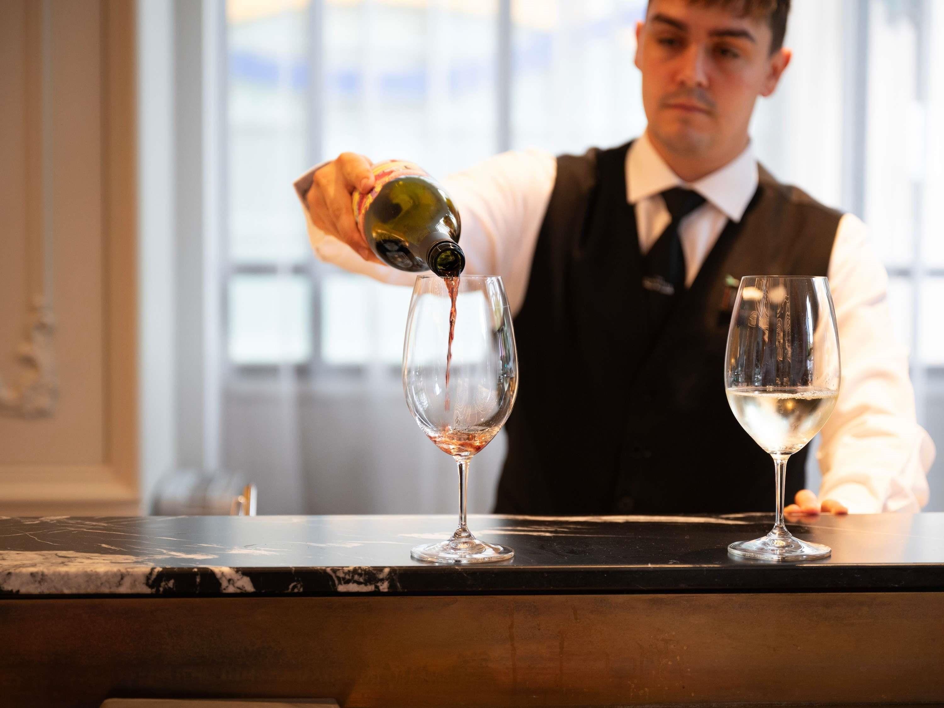 Un bartender sirviendo una bebida en una copa de vino.