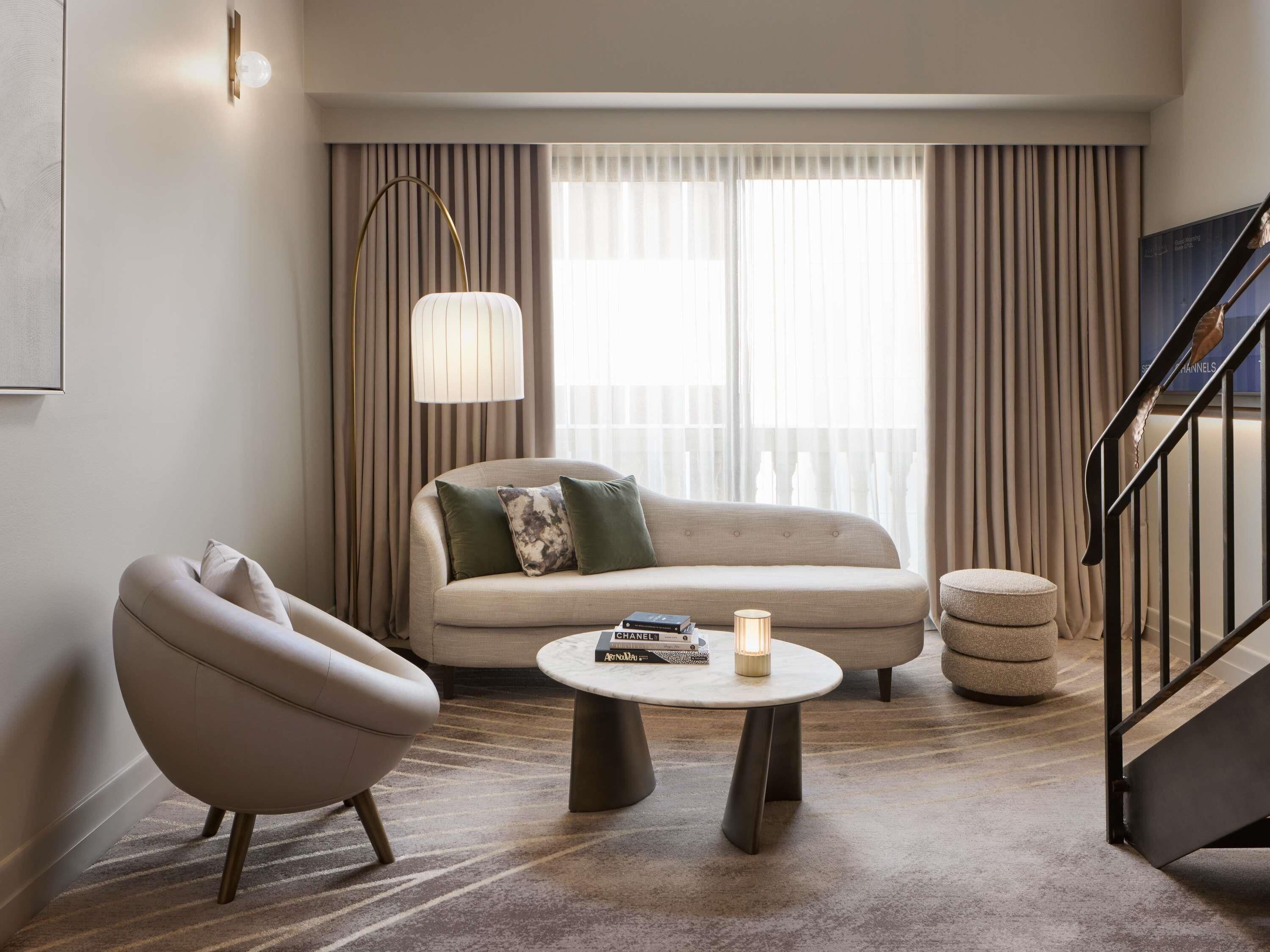 A modern living room with a sofa, armchair, and a round coffee table.